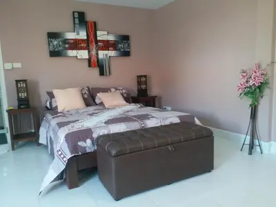 a bedroom with a bed and a ottoman at Résidence Chez Nous Phuket in Rawai Beach