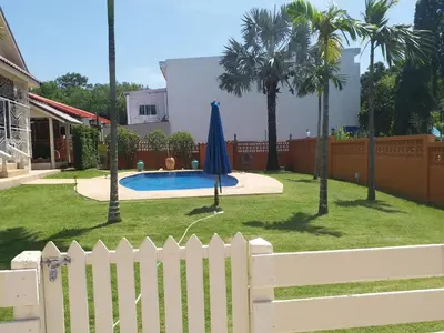 a white fence with a blue umbrella in a yard at Résidence Chez Nous Phuket in Rawai Beach