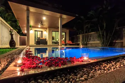 a pool with red flowers and candles in front of a house at Phuket Pool Residence - Adults only in Rawai Beach