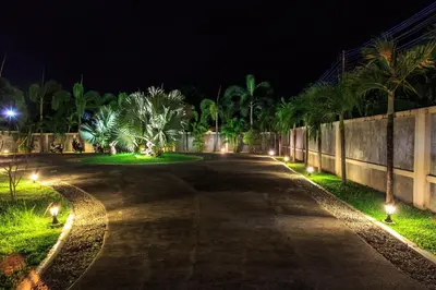 an empty road at night with palm trees and lights at Phuket Pool Residence - Adults only in Rawai Beach