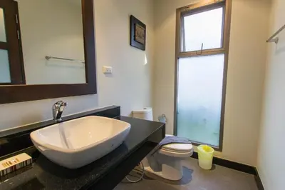 a bathroom with a sink and a toilet and a mirror at Emerald Pool Villa Lush Villa On A Sunny Island in Nai Harn Beach