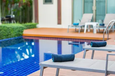 a pool with two lounge chairs and a swimming pool at Emerald Pool Villa Lush Villa On A Sunny Island in Nai Harn Beach