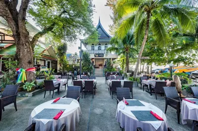 a restaurant with tables and chairs in front of a building at Thai Kamala Beach Front in Kamala Beach