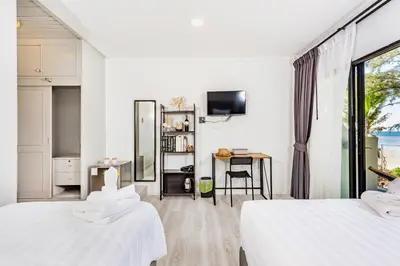 a white room with two beds and a desk at Thai Kamala Beach Front in Kamala Beach
