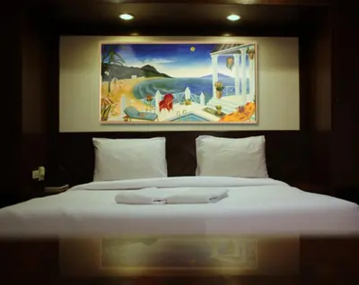 a bedroom with a large white bed with a painting on the wall at Karon Cafe Inn in Karon Beach