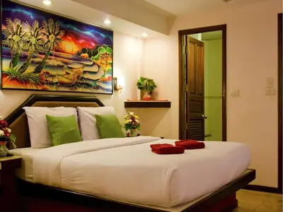 a bedroom with a large white bed with a painting on the wall at Paradise Inn in Karon Beach