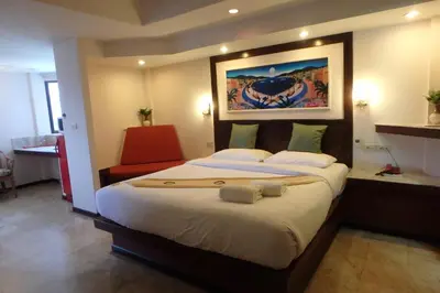 a bedroom with a large bed and a red chair at Paradise Inn in Karon Beach