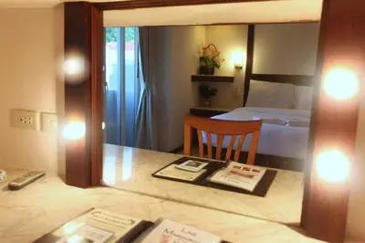 a hotel room with a bed and a table with a mirror at Paradise Inn in Karon Beach