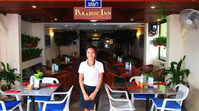 a woman standing in front of a restaurant at Paradise Inn in Karon Beach