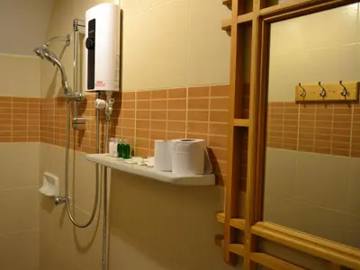 a bathroom with a shower and a sink with towels at Phuket Campground in Mai Khao Beach