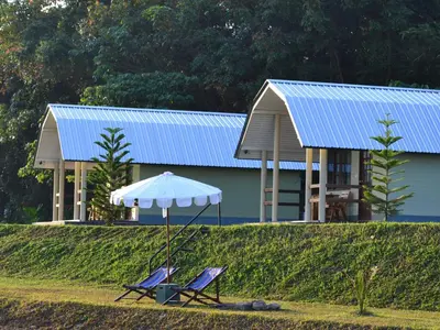 two chairs and an umbrella in front of a building at Phuket Campground in Mai Khao Beach