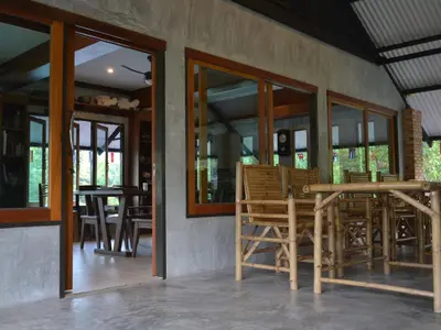 a dining room with chairs and tables and windows at Phuket Campground in Mai Khao Beach