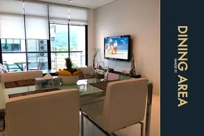 a dining room with a table with chairs and a television at 3 BR Stylish Condo with Private Rooftop Pool in Kamala Beach