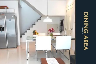 a kitchen with a table and white chairs and a staircase at 3 BR Stylish Condo with Private Rooftop Pool in Kamala Beach