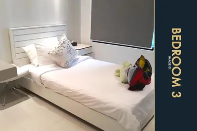 a bed with white sheets and pillows and a desk at 3 BR Stylish Condo with Private Rooftop Pool in Kamala Beach