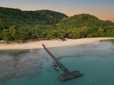 a boat in the water next to a beach at Cruiser Island By Swiss-Belhotel in Ko Lone