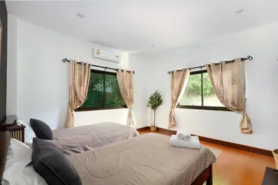 a living room with two beds and two windows at Beachfront pool villa in Kamala Beach