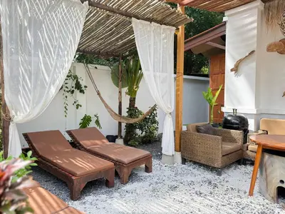 a patio with a hammock and a chair and a table at Beachfront pool villa in Kamala Beach