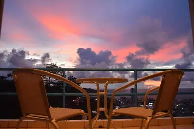 two chairs sitting on a balcony with a sunset at Residy Retreat x Baan Suan Villa in Patong Beach