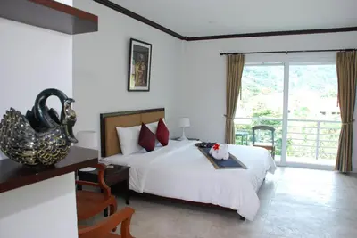a bedroom with a large bed and a balcony at Phukamala Suite in Kamala Beach