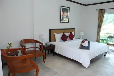 a bedroom with a bed and a desk and a chair at Phukamala Suite in Kamala Beach