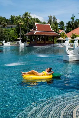 a woman laying on a raft in the water at a resort at Amatara Welleisure Resort in Panwa Beach