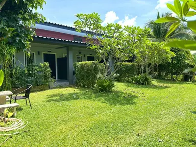 a house with a garden and a bench in front of it at Buncha Place in Bang Tao Beach