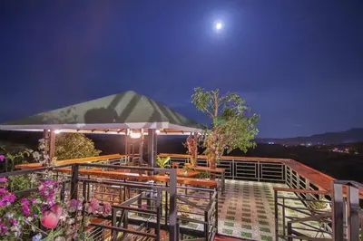 a deck with chairs and an umbrella at night at Happy Mountain Airport Resort in Nai Yang Beach