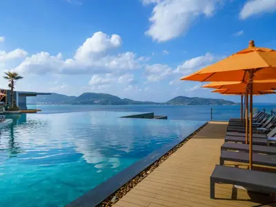 a pool with chairs and an umbrella and the water at Kalima Resort and Spa in Patong Beach