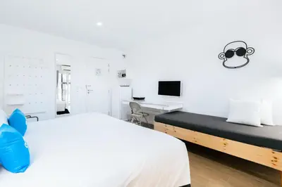 a white bedroom with a bed and a desk at Blu Monkey Bed & Breakfast Phuket in Phuket Town