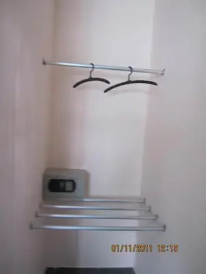 a closet with three shelves and a clock on the wall at Popeye Guesthouse in Ao Nang Beach