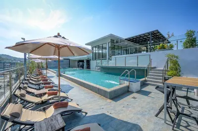 a pool with chairs and an umbrella next to a building at Zenseana Resort & Spa - Patong, Phuket in Patong Beach