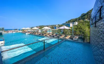 a large swimming pool with chairs and the ocean at Zenseana Resort & Spa - Patong, Phuket in Patong Beach