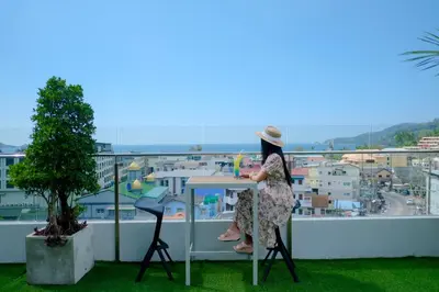 a woman sitting at a table on a balcony at Zenseana Resort & Spa - Patong, Phuket in Patong Beach