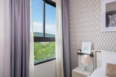 a bedroom with a window and a bed with a lamp at Bangtao,Layan beach apartment in Bang Tao Beach