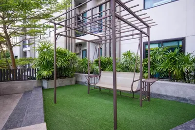 a bench on a lawn in front of a building at Bangtao,Layan beach apartment in Bang Tao Beach
