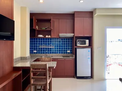 a kitchen with brown cabinets and a white refrigerator at Baan Sudarat Hotel in Patong Beach