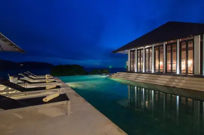 a pool with lounge chairs and a building at night at Villa Princess Stephanie in Kata Beach