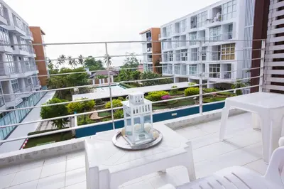 a balcony with white furniture and a view of buildings at At Seacondo-2 Bedrooms-B35 in Klong Muang Beach