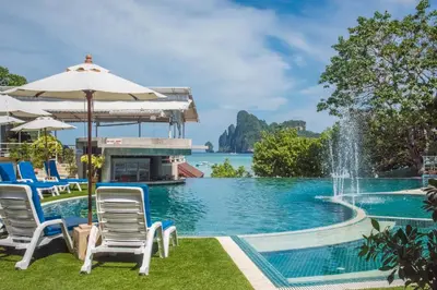 a pool with chairs and an umbrella and a fountain at PP Charlie Beach Resort in Phi Phi Don