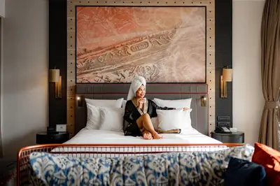 a woman sitting on a bed in a hotel room at Hotel Indigo Phuket Patong by IHG in Patong Beach