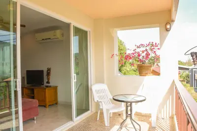 a balcony with a table and chairs and a window at Baan Rosa Bangtao Beach in Bang Tao Beach