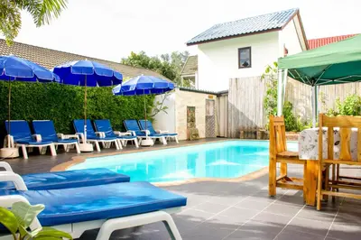 a swimming pool with blue chairs and umbrellas at Baan Rosa Bangtao Beach in Bang Tao Beach