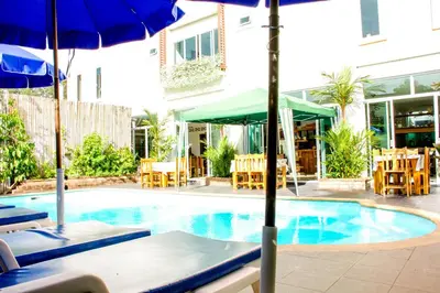 a swimming pool with umbrellas and tables and chairs at Baan Rosa Bangtao Beach in Bang Tao Beach