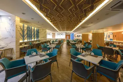 a dining room with tables and blue chairs at The Beachfront Hotel Phuket in Rawai Beach