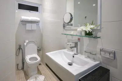 a white bathroom with a sink and a toilet at The Beachfront Hotel Phuket in Rawai Beach