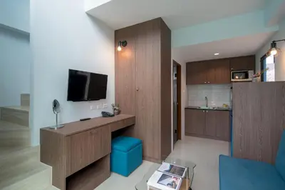 a living room with a tv and a blue chair at Peace Blue Naiharn Naturist Resort Phuket SHA Extra Plus in Rawai Beach