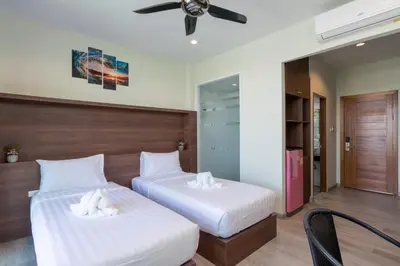 two beds in a room with a ceiling fan at Peace Blue Naiharn Naturist Resort Phuket SHA Extra Plus in Rawai Beach