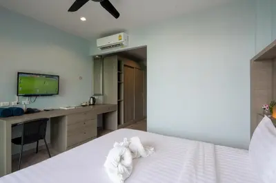 a bedroom with a bed with a desk and a tv at Peace Blue Naiharn Naturist Resort Phuket SHA Extra Plus in Rawai Beach