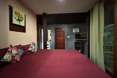 a bedroom with a red bed with two pillows on it at Tann Anda Resort in Thalang